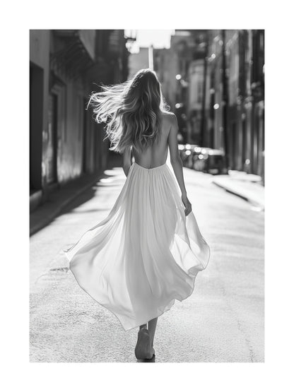 Black and white poster of a woman in a dress walking through a city street