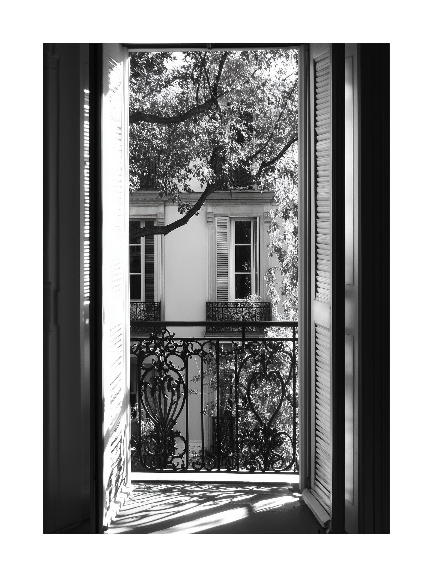 Black and white photo of view through open balcony doors in Paris