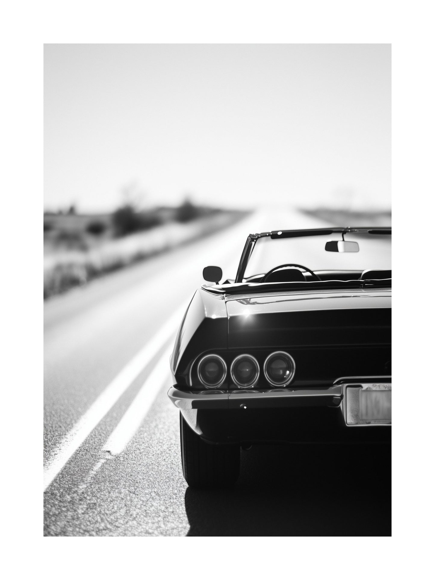 Rear view of a vintage convertible driving on an open road in black and white
