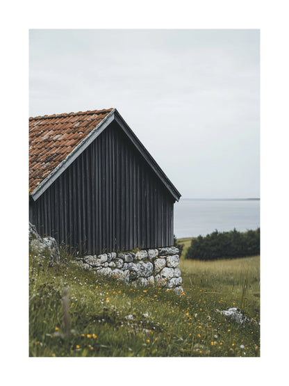Rustic wooden barn on Gotland coast with stone foundation and ocean view