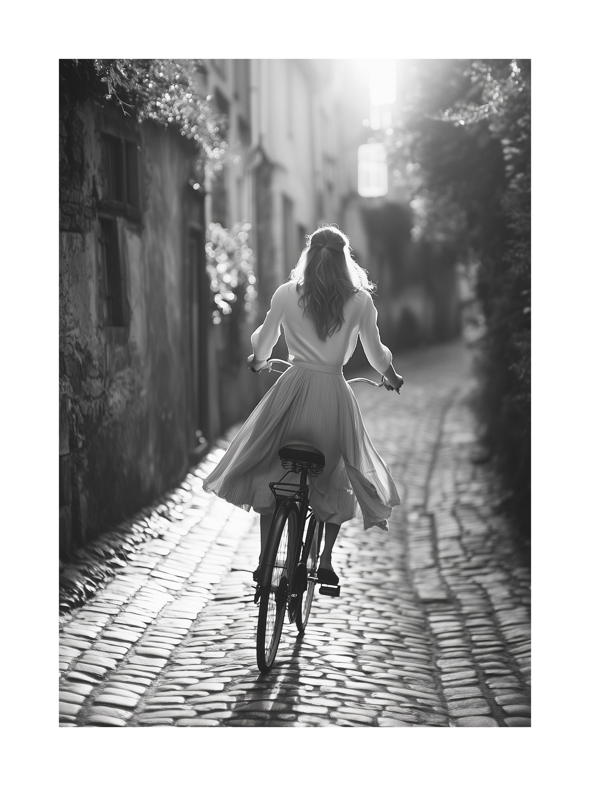 Black and white photo of a woman riding a bicycle on cobblestone street