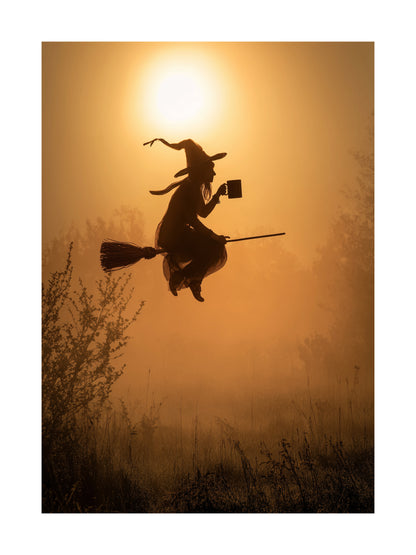 Halloween poster of witch flying on broomstick holding coffee mug in golden sunrise