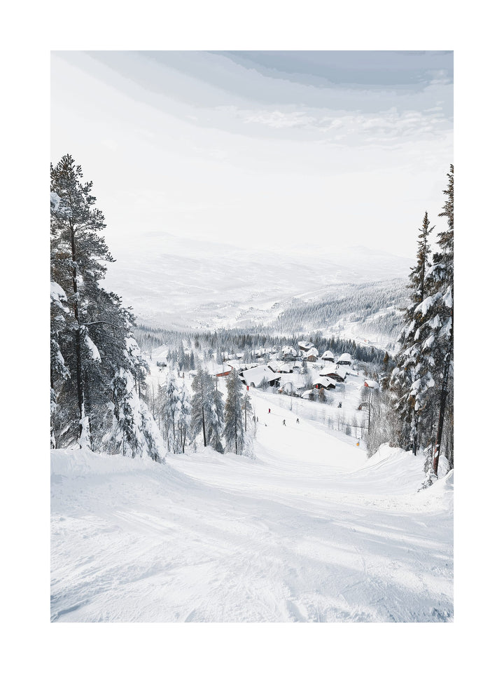 Snowy ski slope overlooking a mountain village with trees and cabins.