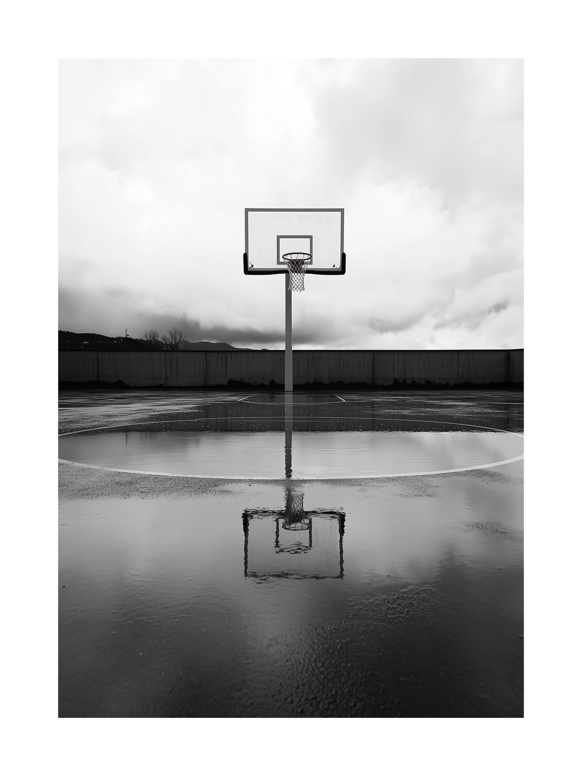 Black and white photo of basketball hoop and reflection on wet court