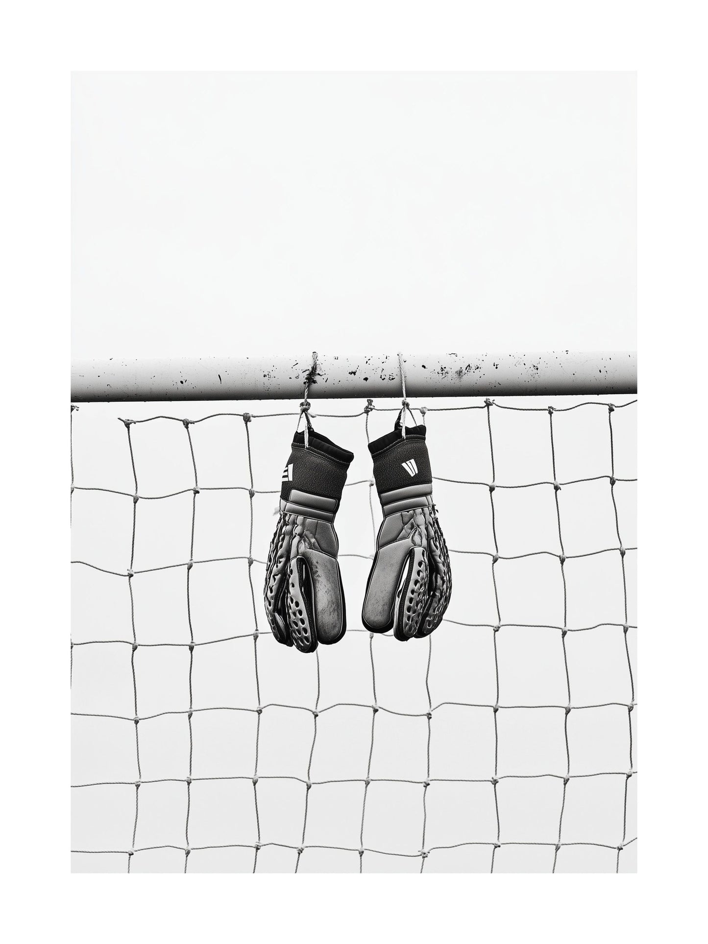 Black and white image of goalkeeper gloves hanging on goalpost