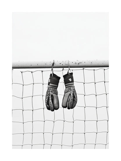 Black and white image of goalkeeper gloves hanging on goalpost