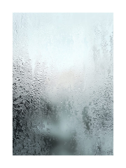 Close-up of frosty condensation on a frozen glass surface with soft light.