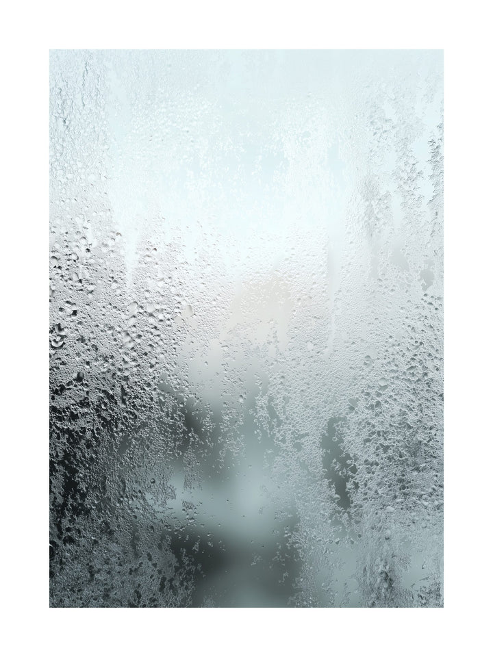 Close-up of frosty condensation on a frozen glass surface with soft light.
