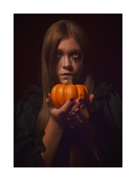 Halloween poster of a girl with glowing eyes holding a pumpkin